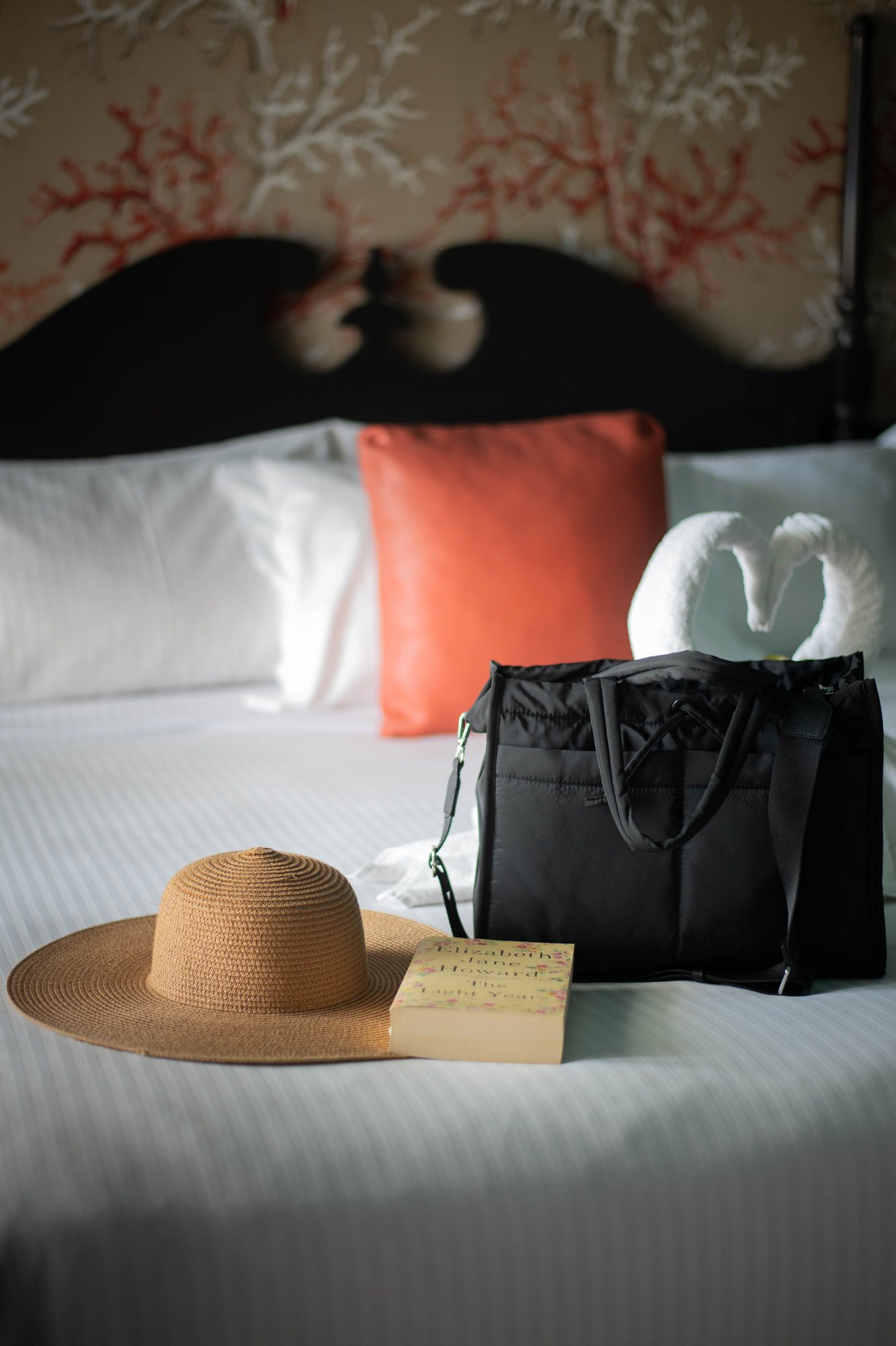 Chapeau de paille, sac et livre posés sur le lit d'une chambre de la Villa Delisle