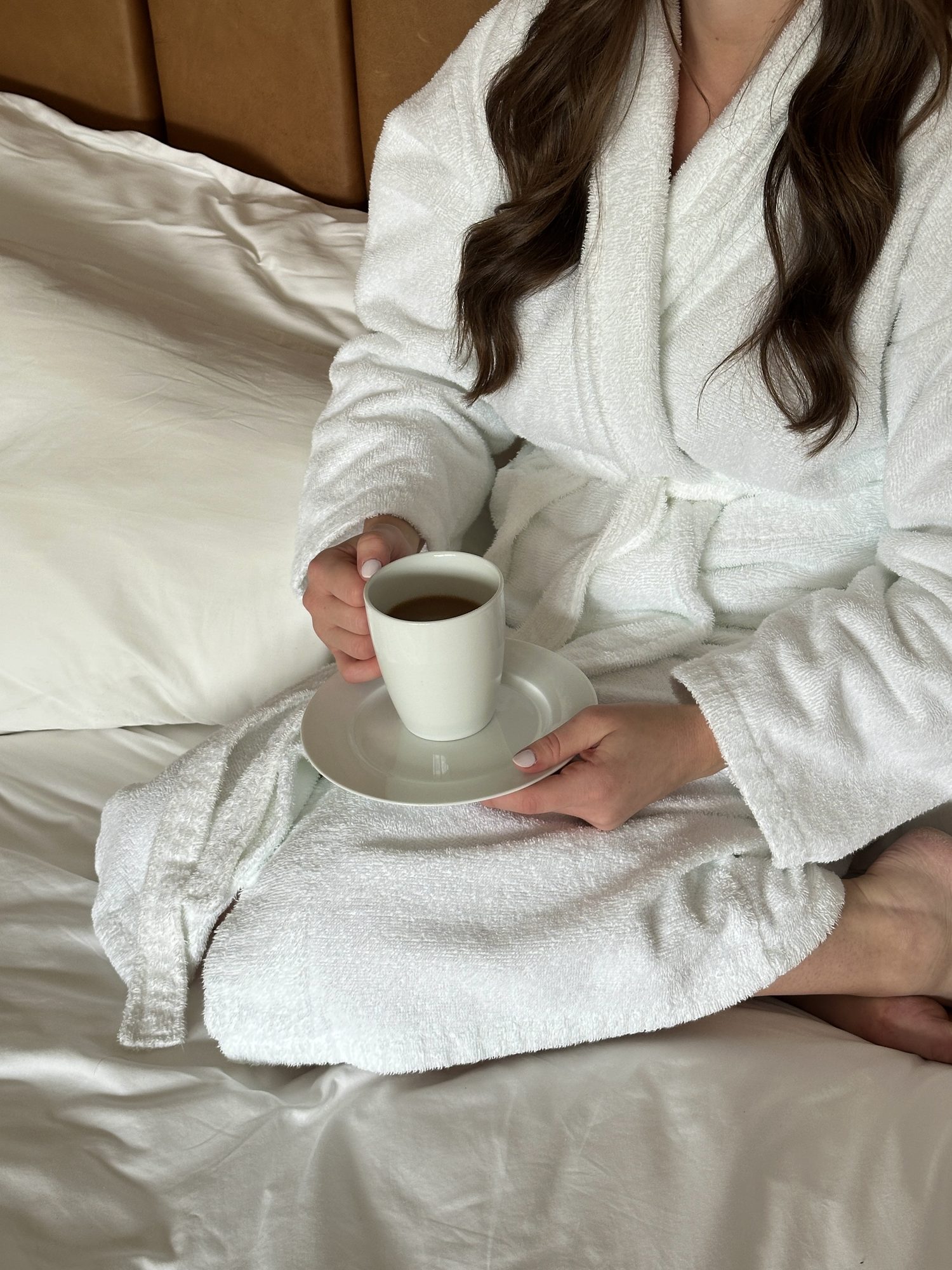 Cliente en peignoir blanc savourant un café au lit